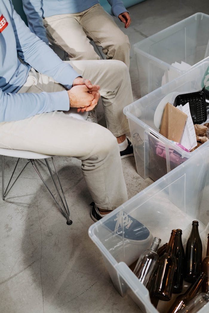 Volunteers sitting and sorting plastic, paper, and glass bottles for recycling.